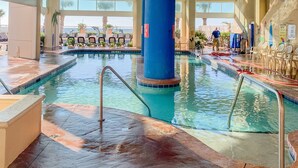 An indoor swimming pool with clear water, surrounded by lounge chairs and a large blue pillar. - ⋆𖦹NEW❀Amazing Direct OceanFront/Spacious/Pristine/Indr-WaterParks 2BR2BA2Balcs (Myrtle Beach)
