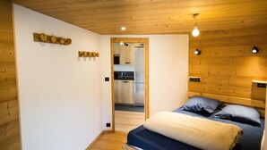 Een slaapkamer met een houten plafond, een bed met blauw-witte beddengoed, en een houten wandplank.