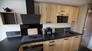 Een moderne keuken met houten kastjes, een zwart aanrecht, een ingebouwde oven en een roestvrijstalen koelkast.