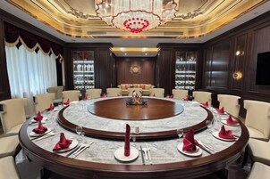Una sala de reuniones formal con una mesa redonda, sillas y una araña.