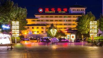 A hotel with a prominent sign, multiple floors, and a parking lot.