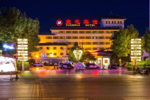 Un hôtel reconnaissable à son enseigne bien visible, avec de nombreux étages et un parking.