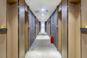 Pasillo de hotel con puertas numeradas 2119 y 2101, un extintor rojo y una alfombra estampada.