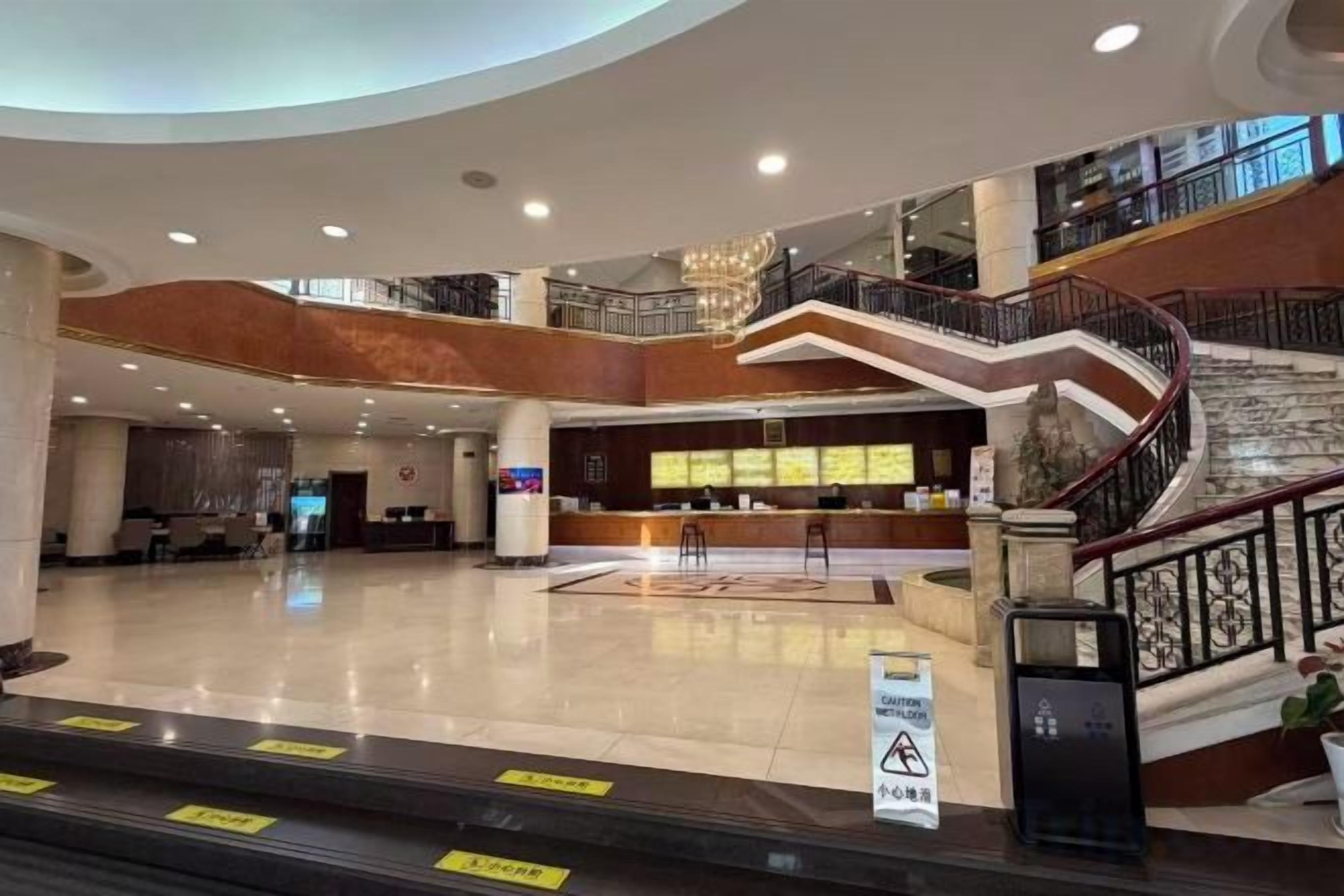 A spacious lobby with a reception desk, a staircase, and a clear view of the upper floor.