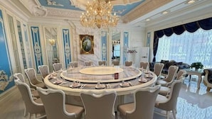 Une table de salle à manger ronde, avec des chaises, un lustre et un tableau au mur.