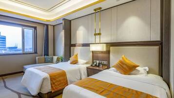 A hotel room with two beds, a nightstand, a lamp, and a view of the city.