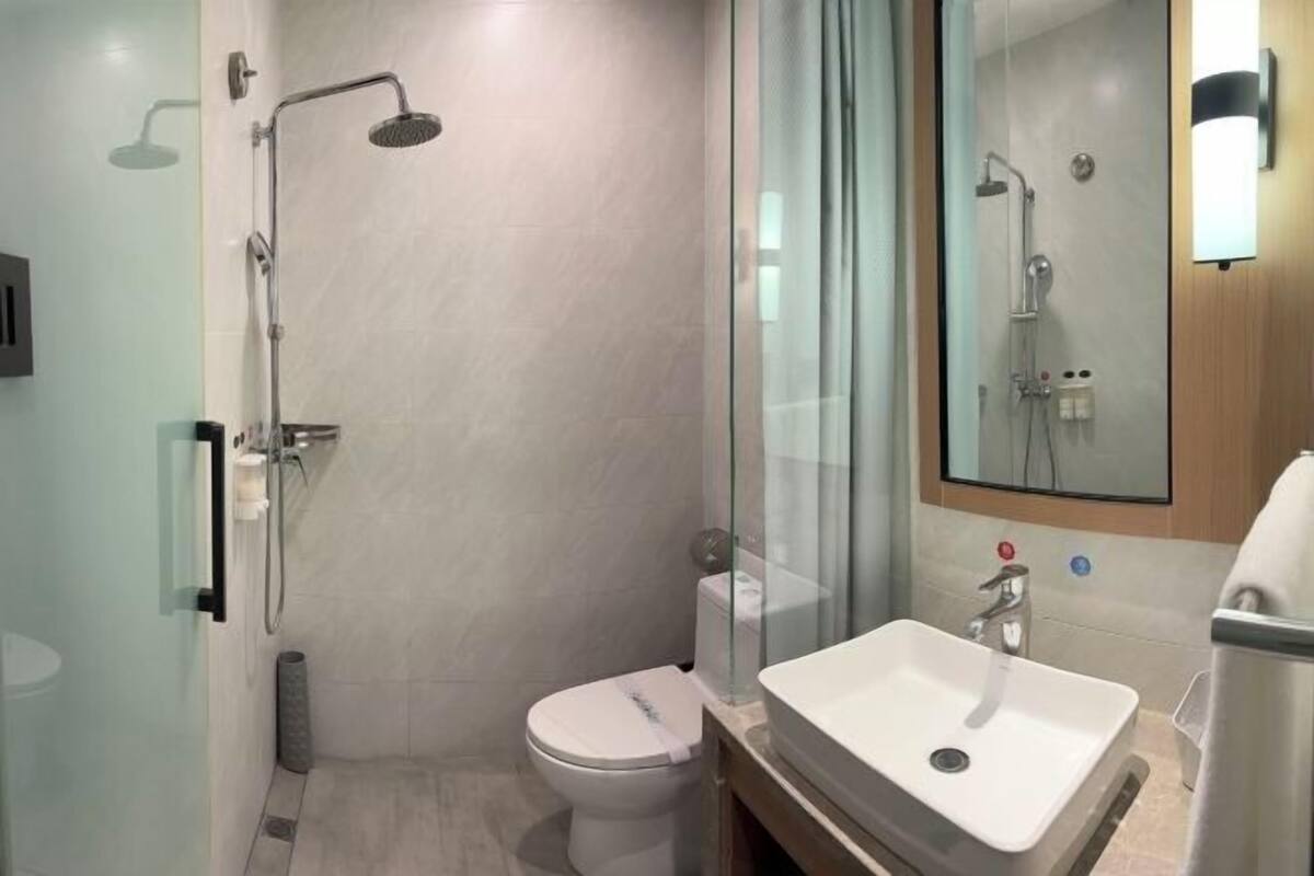 A modern bathroom with a glass shower enclosure, a white toilet, and a sink with a mirror above it.