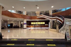 Un hall d’entrée spacieux avec un comptoir d’accueil, un escalier et un plafond haut.
