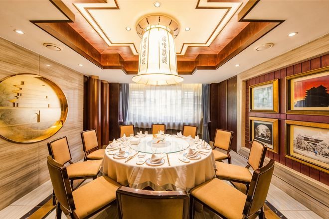 A round dining table with chairs, a chandelier, and framed pictures on the walls.