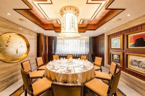 Una mesa de comedor redonda con sillas, una lámpara de araña y cuadros en las paredes.