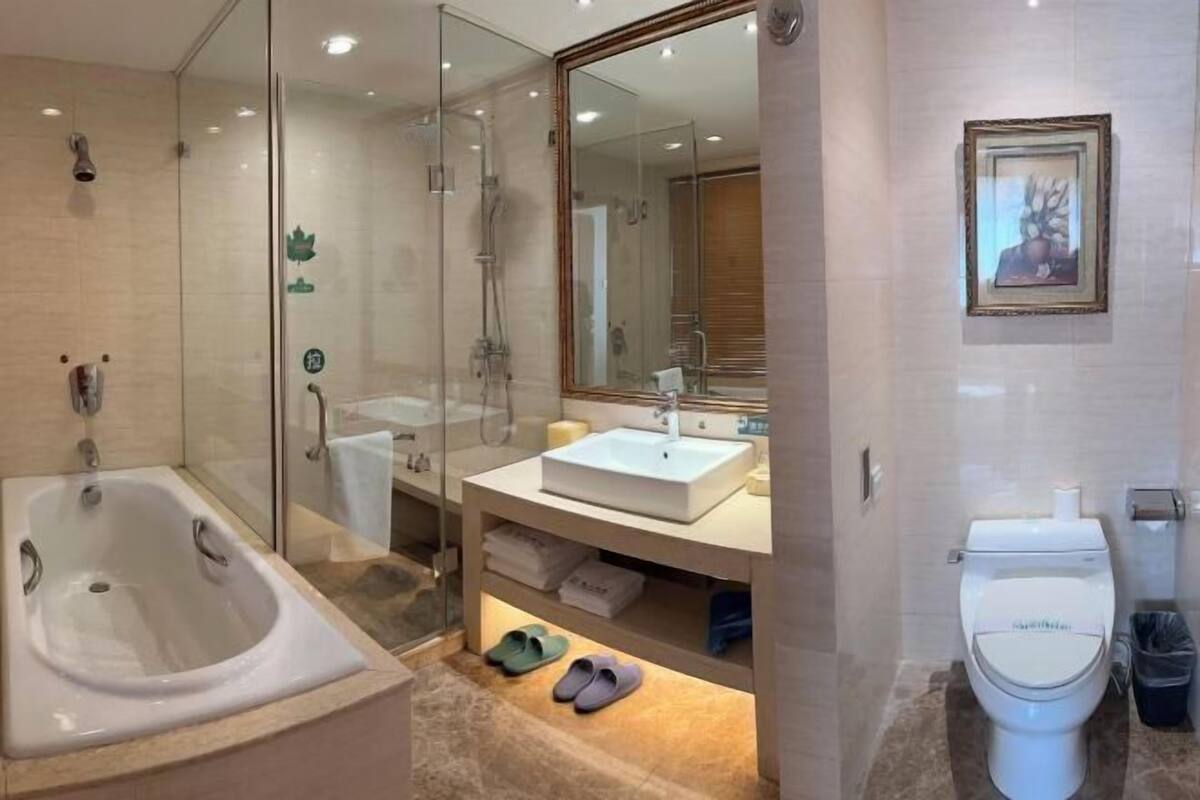 A modern bathroom with a glass-enclosed shower, a freestanding bathtub, a sink with a mirror, and a toilet.