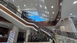 Un hall d’hôtel doté d’un escalier central, de plusieurs niveaux et d’un comptoir d’accueil.