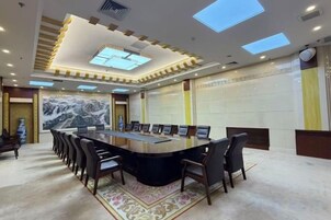 Un salón de conferencias con una larga mesa, sillas y un amplio ventanal.