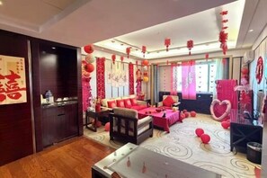 A room with a sofa, a dining table, and a decorative wall with red lanterns.