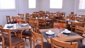 A dining area with multiple tables and chairs, arranged in a grid pattern. - Prime Moc Hotel (Montes Claros)