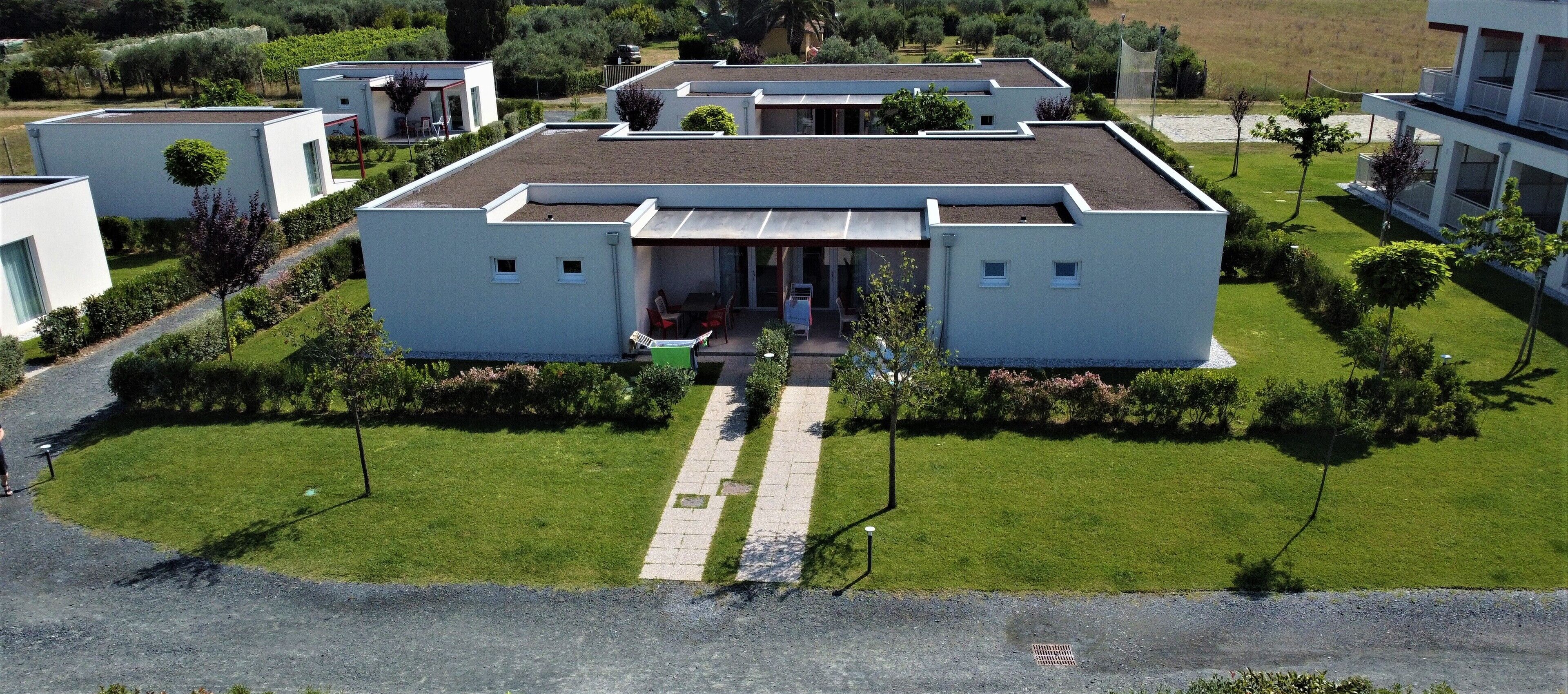 A modern residential building with a flat roof, a central entrance, and a well-maintained lawn.