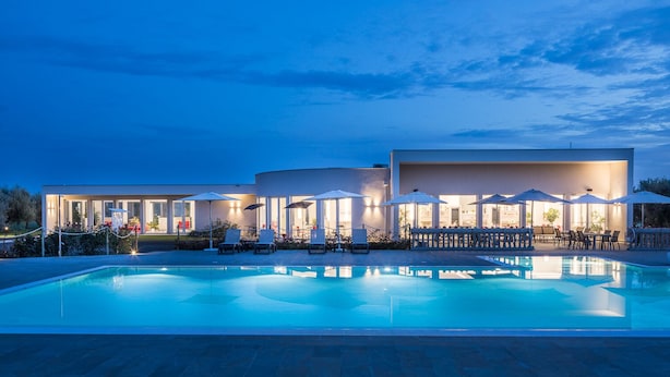 Ein modernes Hotel mit Schwimmbad, Außenbereich und einer gut beleuchteten Fassade.