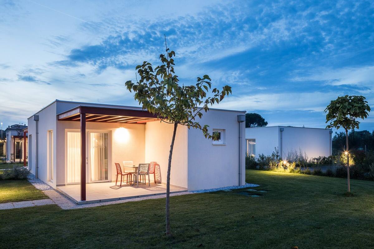 A modern house with a covered patio, a small garden, and a clear sky.