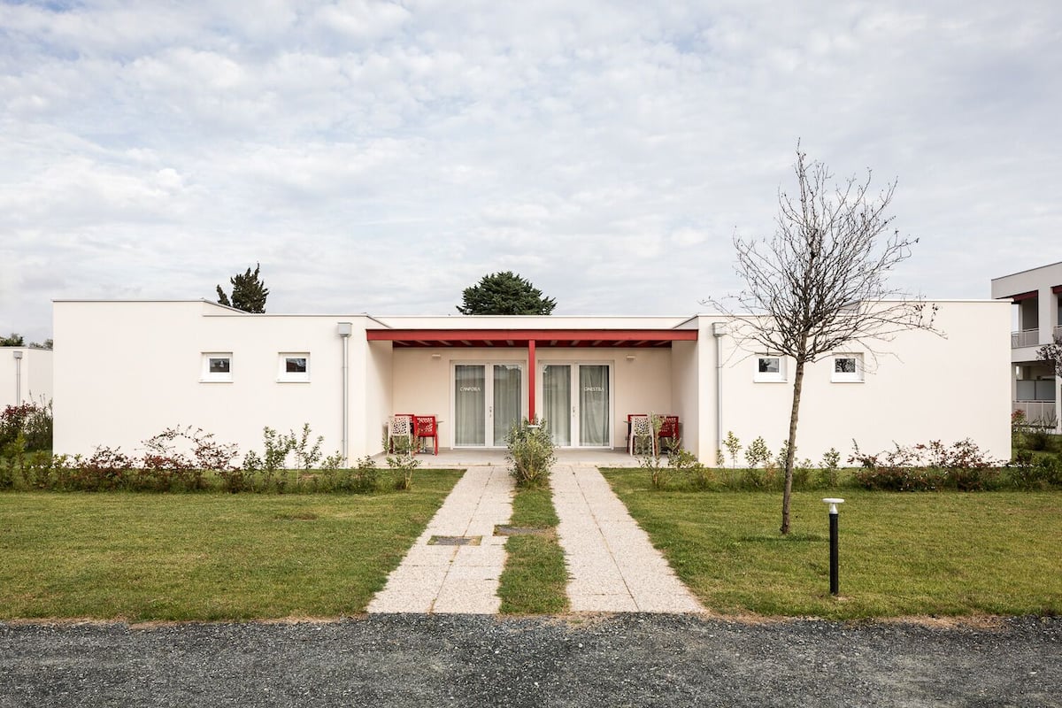 A modern building with a central entrance, two side wings, and a paved pathway leading to the entrance.
