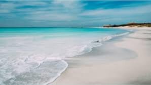 Ein Strand mit klarem türkisblauem Wasser und einem sandigen Ufer.