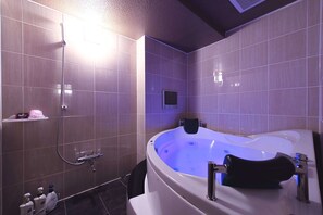 A modern bathroom with a large bathtub, a shower area, and a small shelf with toiletries. - alo alo - Adults Only (Fujikawaguchiko)