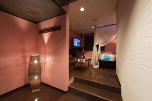 A hotel room with a large vase, a television, a bed with a canopy, and a small table with decorative items. - alo alo - Adults Only (Fujikawaguchiko)