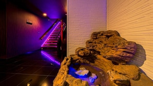 Un interior modern amb una font de pedra i una escala amb il·luminació morada.