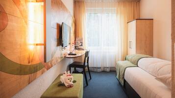 A hotel room with a bed, a desk, a chair, a television, and a window with curtains.