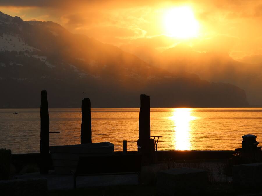Un atardecer sobre una superficie acuática tranquila con montañas al fondo.