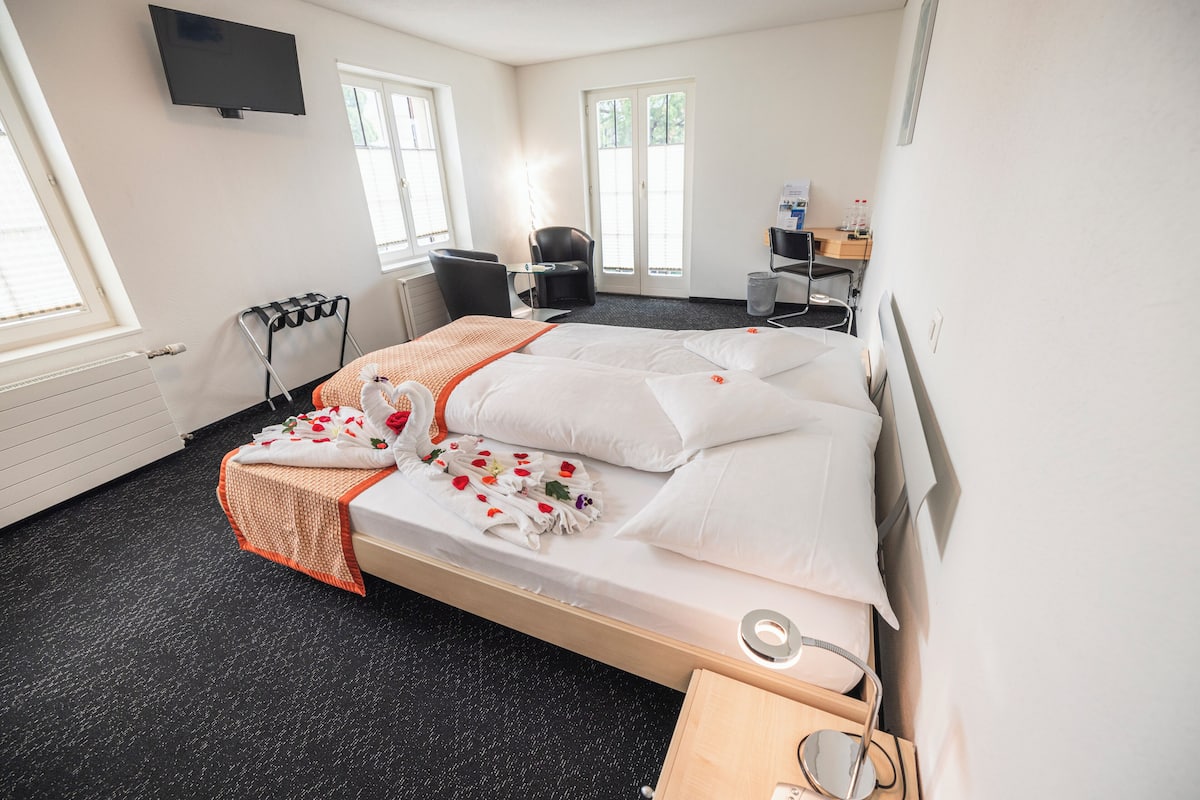 Ein Hotelzimmer mit Bett, Schreibtisch, Stuhl, Fernseher und Fenster.