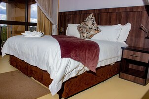 A large bed with white linens, a brown headboard, and a red throw blanket.