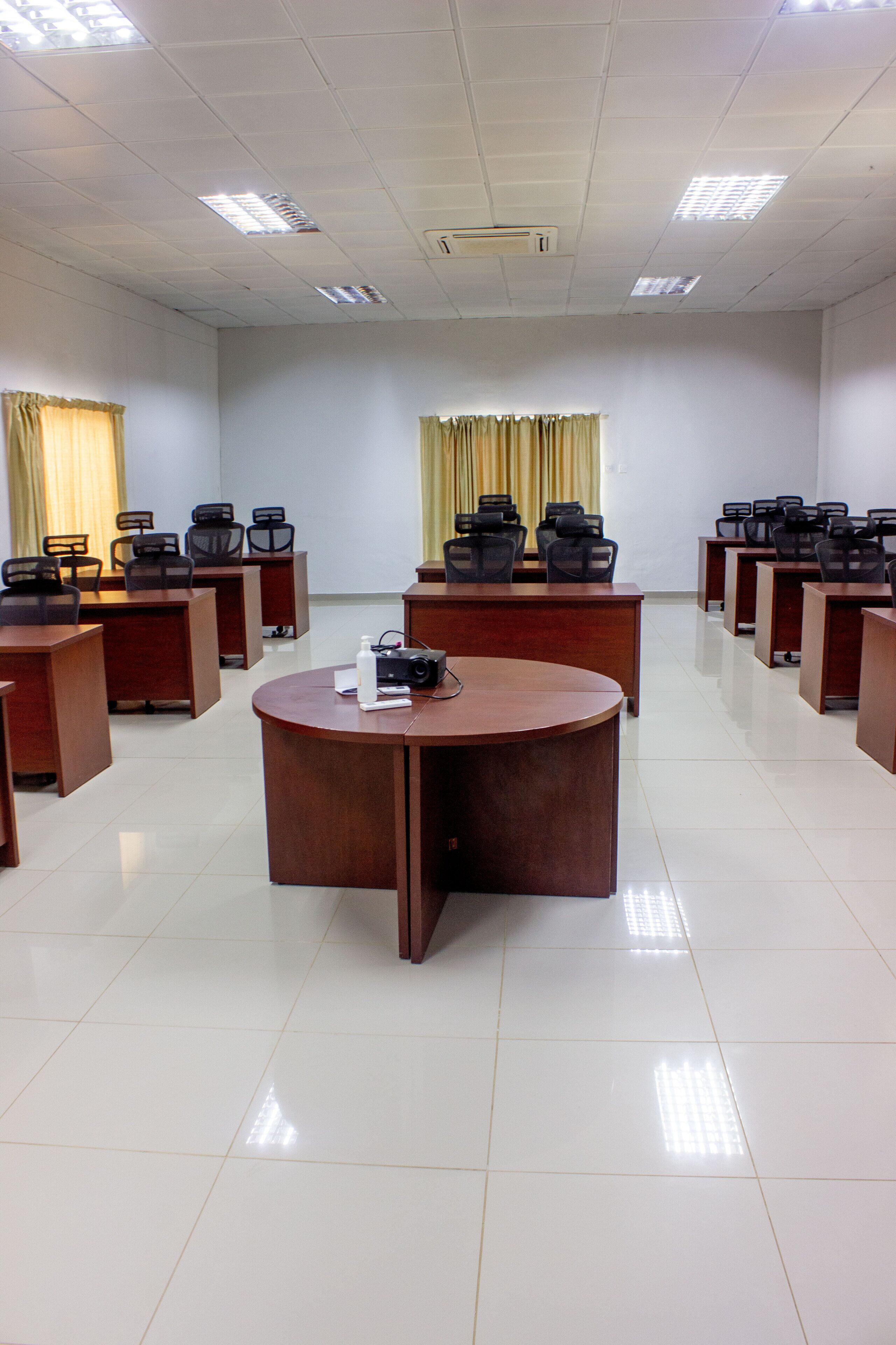 A conference room with multiple tables and chairs, a podium, and a projector.