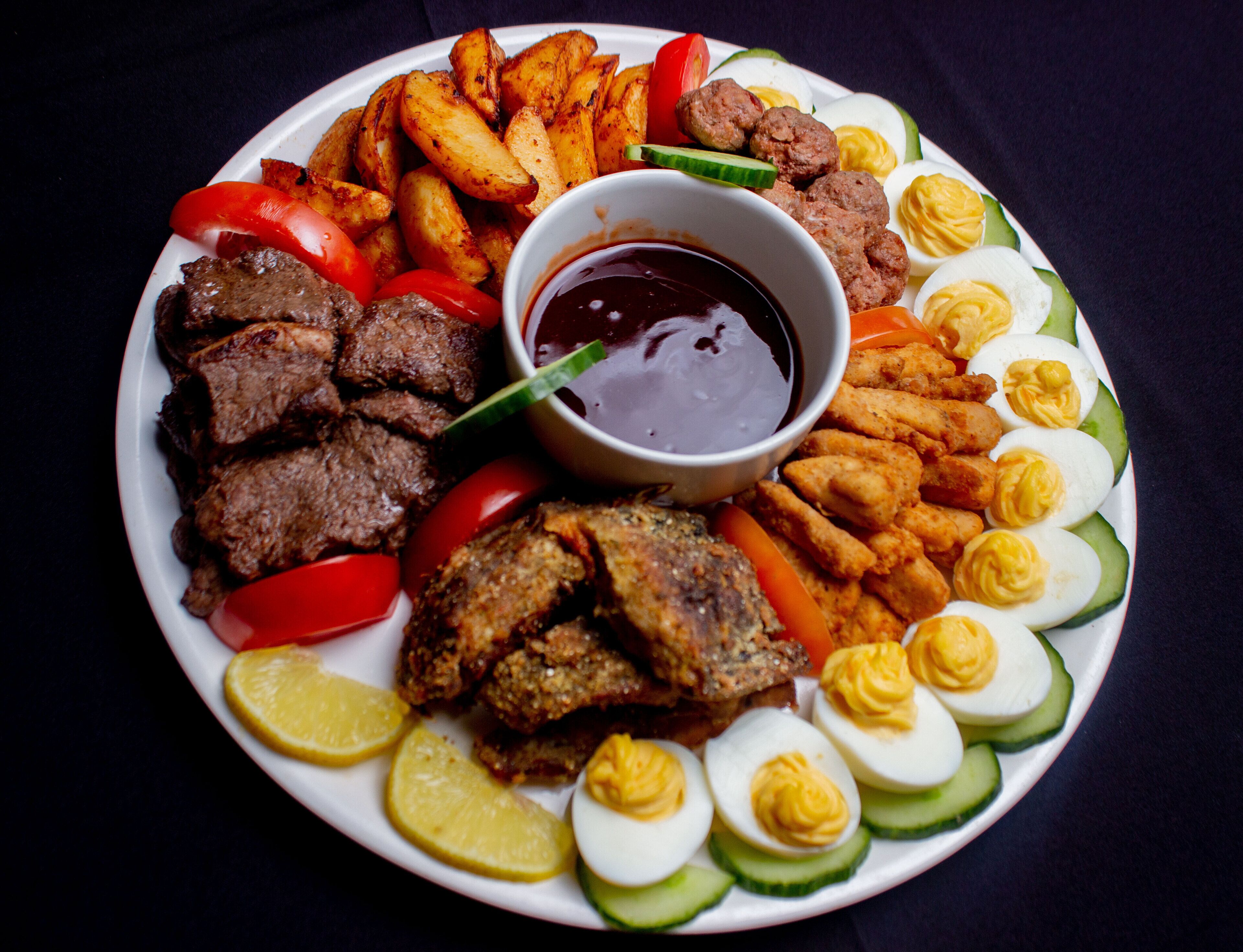 Un plato de comida con carne, papas fritas y huevos cocidos.