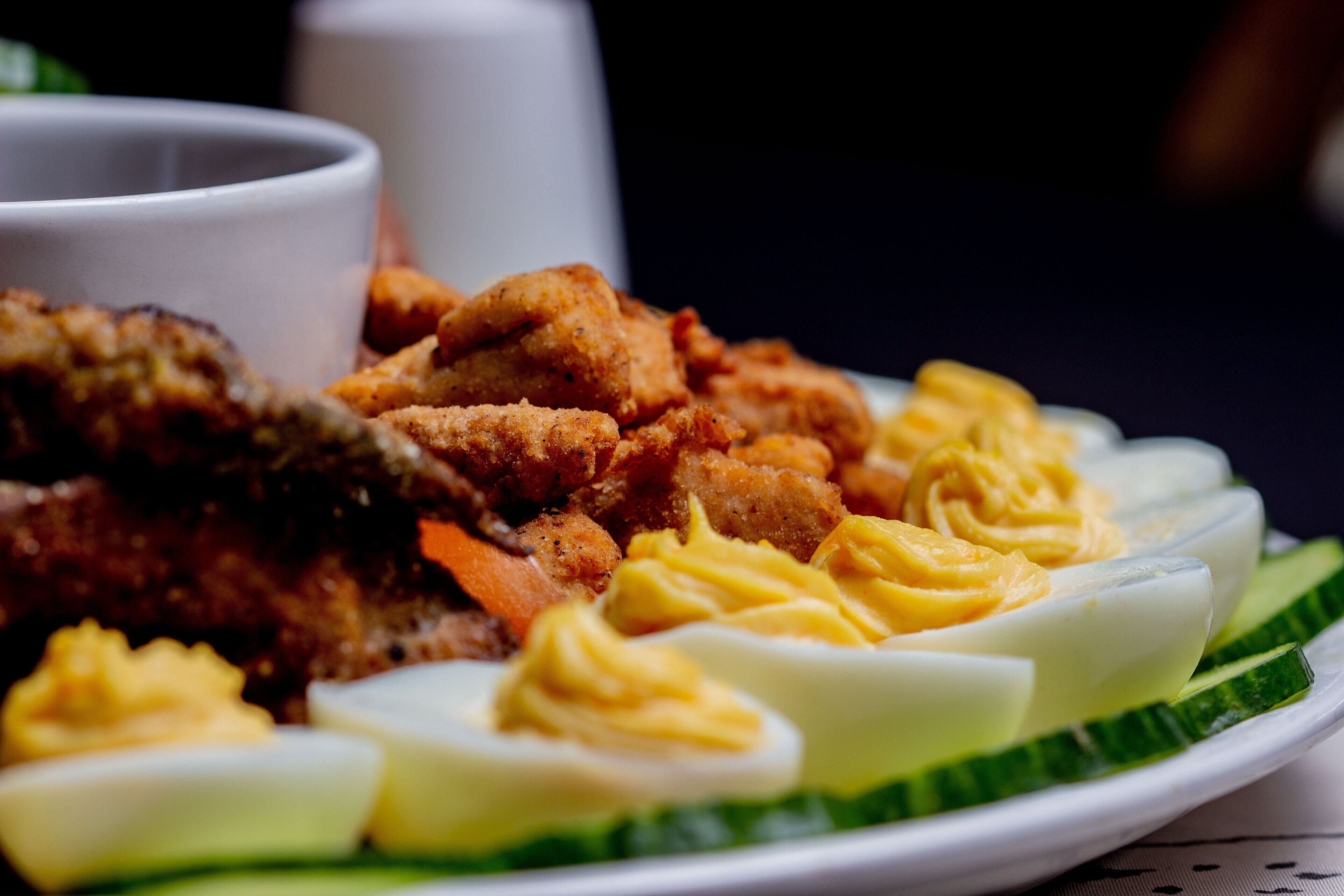 A plate of food including fried items, boiled eggs, and a green vegetable.
