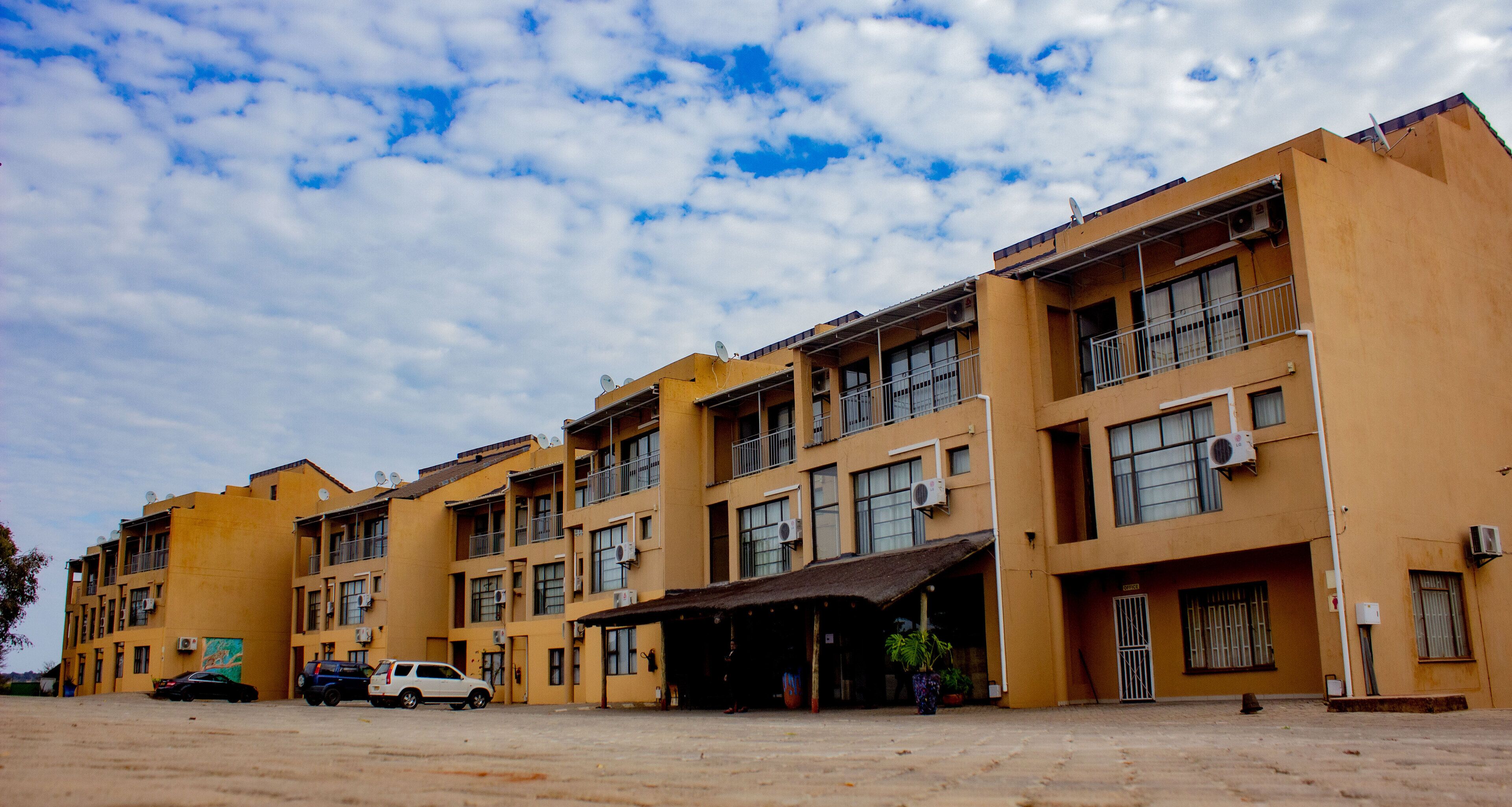 A multi-story building with balconies, air conditioning units, and a covered entrance.