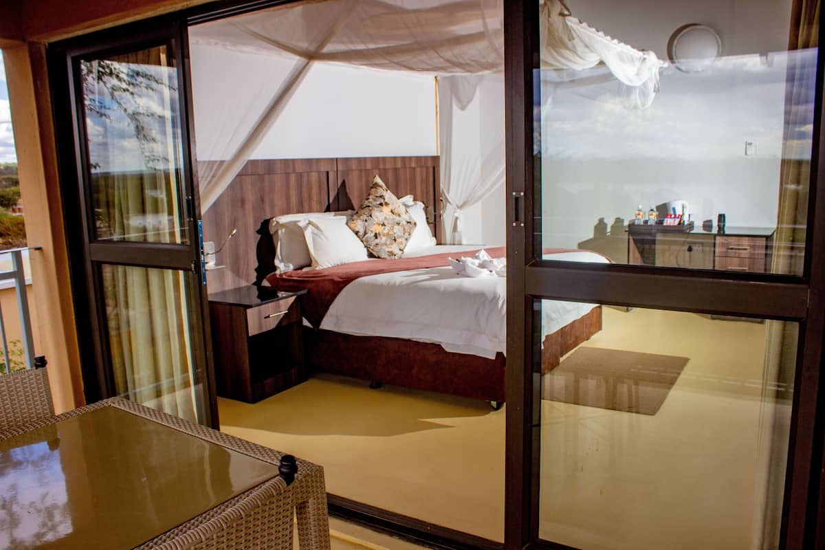Ein Schlafzimmer mit einem Bett, einem Nachttisch und einer Glastür, die zu einem Außenbereich führt.