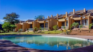 Un hotel con piscina, mobiliario exterior y césped bien cuidado.