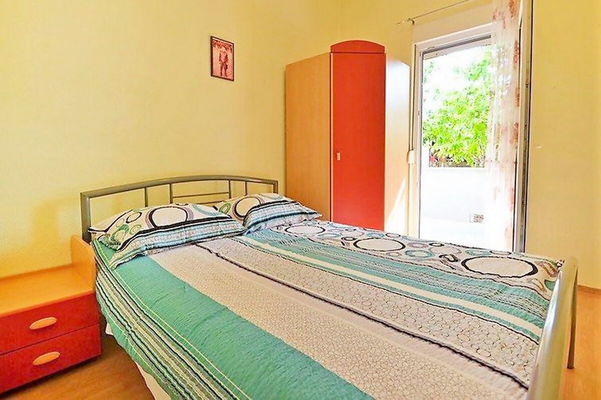 Un dormitori amb un llit, un armari, una taula petita i una finestra amb cortines.