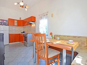 A compact kitchen with wooden cabinets, a dining table with chairs, and a small oven.