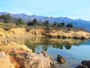 Un paysage naturel comprenant une rivière, un terrain rocheux et des montagnes à l’horizon.