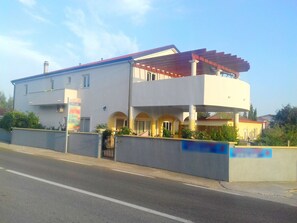 A two-story building with a flat roof, a balcony on the upper floor, and a gated entrance. - Apartments Bucic (Starigrad)
