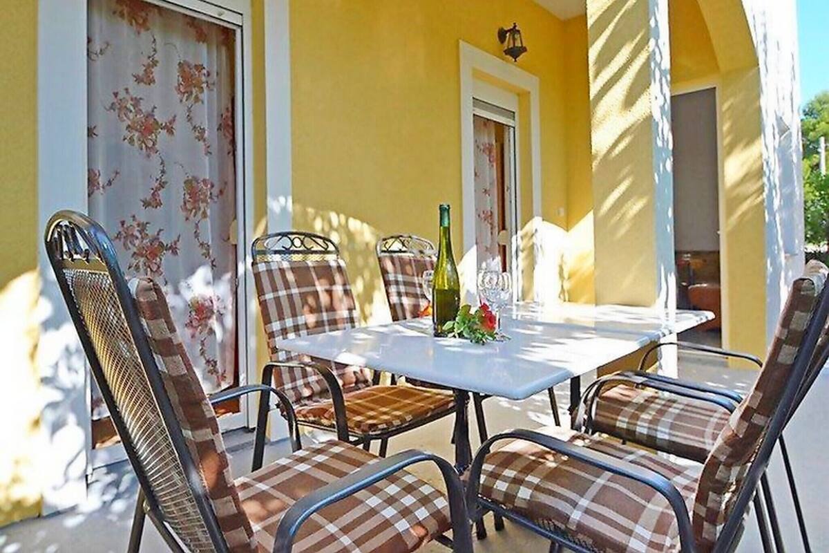 A patio with a table and chairs, a bottle, and a glass.