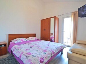 A bedroom with a bed, a wardrobe, a television, and a sliding door. - Apartments Bucic (Starigrad)