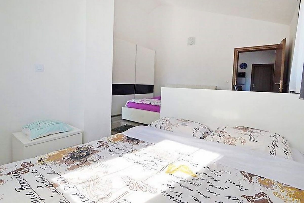 A bedroom with a bed, a nightstand, a wardrobe, and a mirror.