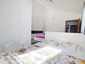 A bedroom with a bed, a nightstand, a wardrobe, and a mirror.