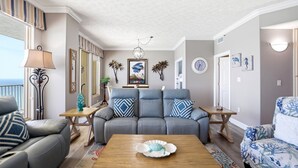 A living room with a sofa, a coffee table, a lamp, and a view of the ocean. - Relaxing Beachfront Condo with Beach Access - Unit 1603 by RedAwning (Panama City Beach)