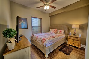 A bedroom with a bed, bedside table, lamp, and a ceiling fan. - Roomy Oceanfront Condo with Breathtaking View and Beachside Pool - Unit 1906 by RedAwning (Panama City Beach)