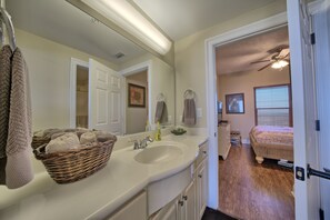 A bathroom with a large mirror, white sink, and a wicker basket filled with towels. - Roomy Oceanfront Condo with Breathtaking View and Beachside Pool - Unit 1906 by RedAwning (Panama City Beach)
