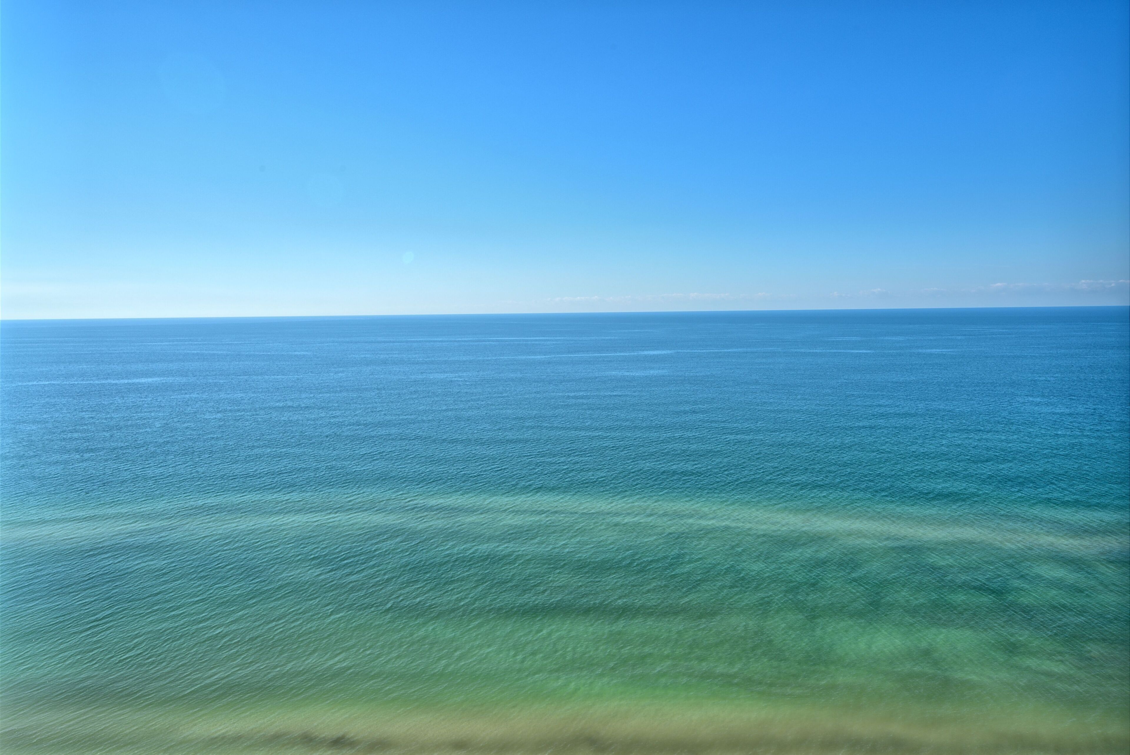 Une vue dégagée sur une mer calme sous un ciel bleu.