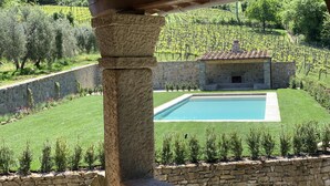 A stone pool with a stone wall and a stone building with a tiled roof in the background. - Villa Pie Vecchia in Chianti (Greve in Chianti)